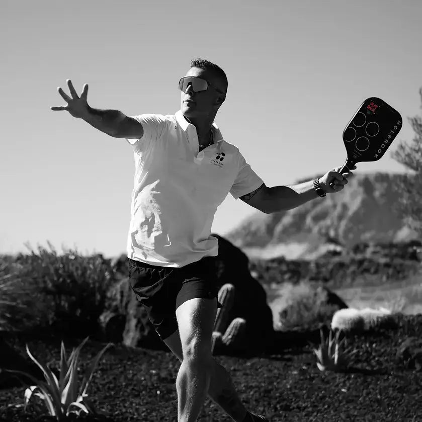 Man playing pickleball with Holbrook ARMA paddle against a scenic backdrop, showcasing active lifestyle.