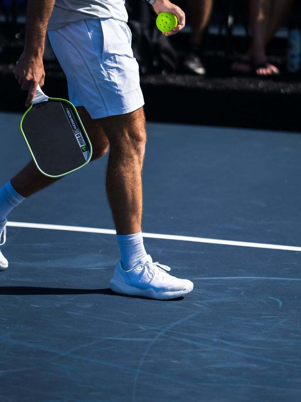 Player holding Joola Kosmos Pro V Surge Green (Global) paddle on the court with ball, in action.