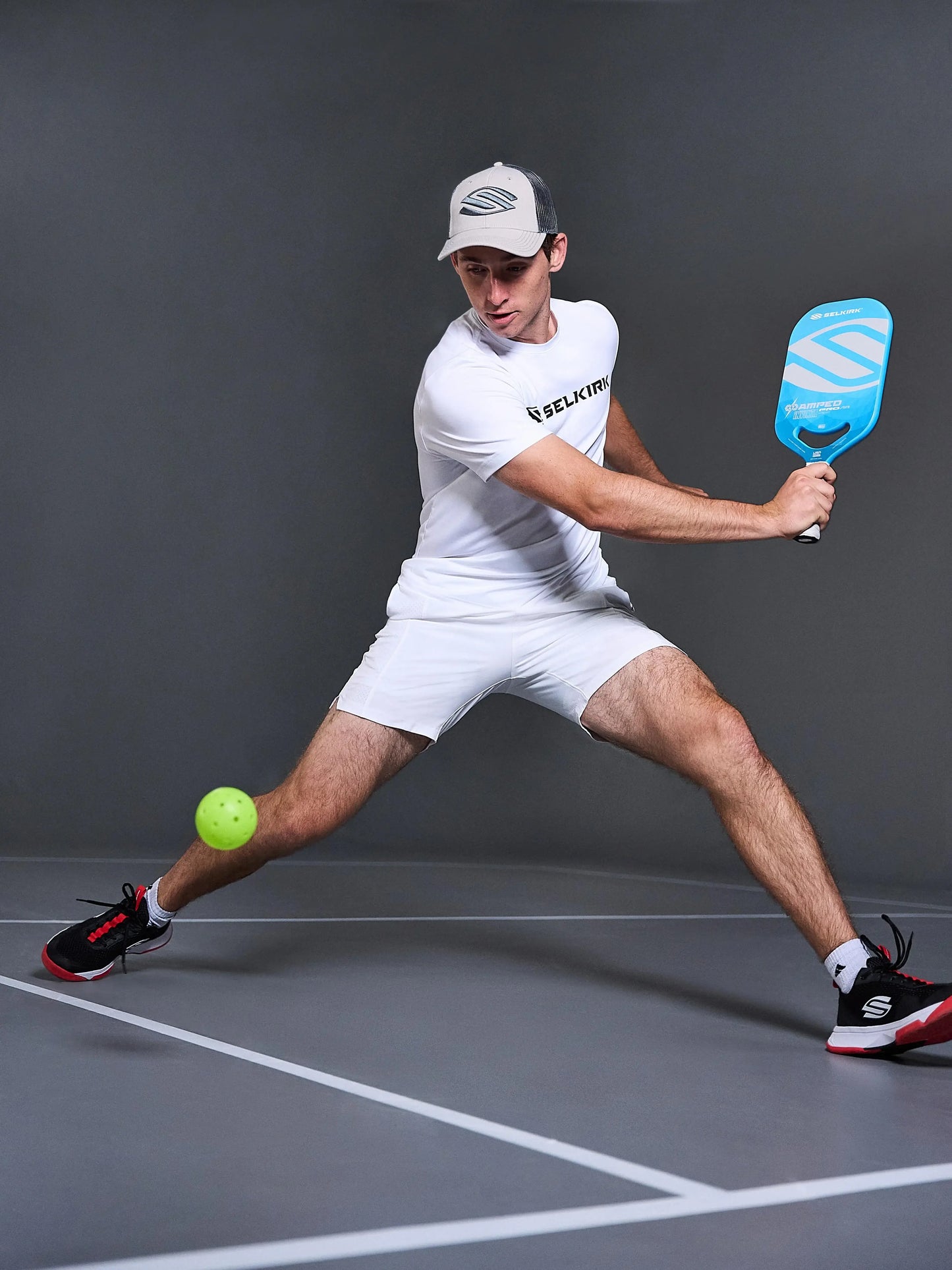 Athlete swinging Selkirk AMPED Pro Air pickleball paddle in action with a green pickleball on court.