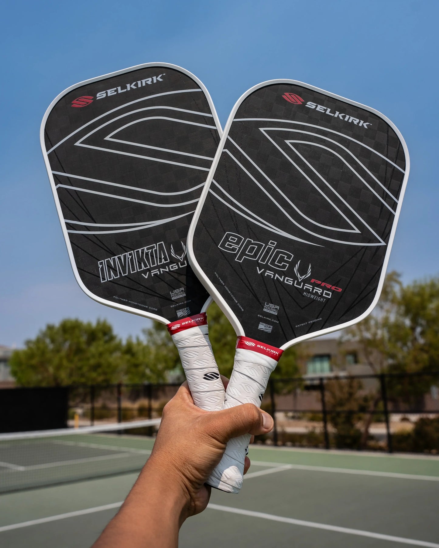 Two Selkirk VANGUARD pickleball paddles, INVICTA and EPIC, showcasing premium carbon fiber design on a court.