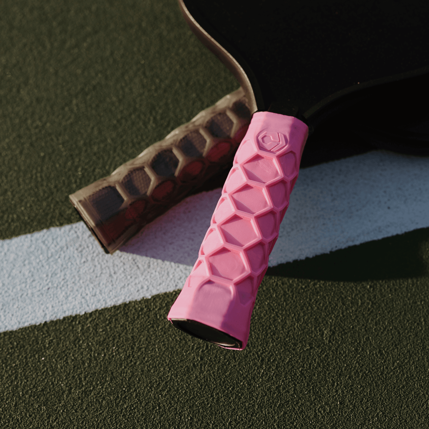Pink Hesacore XS Pickleball Grip with honeycomb design on a paddle absorbing sweat and vibrations for enhanced comfort and efficiency.