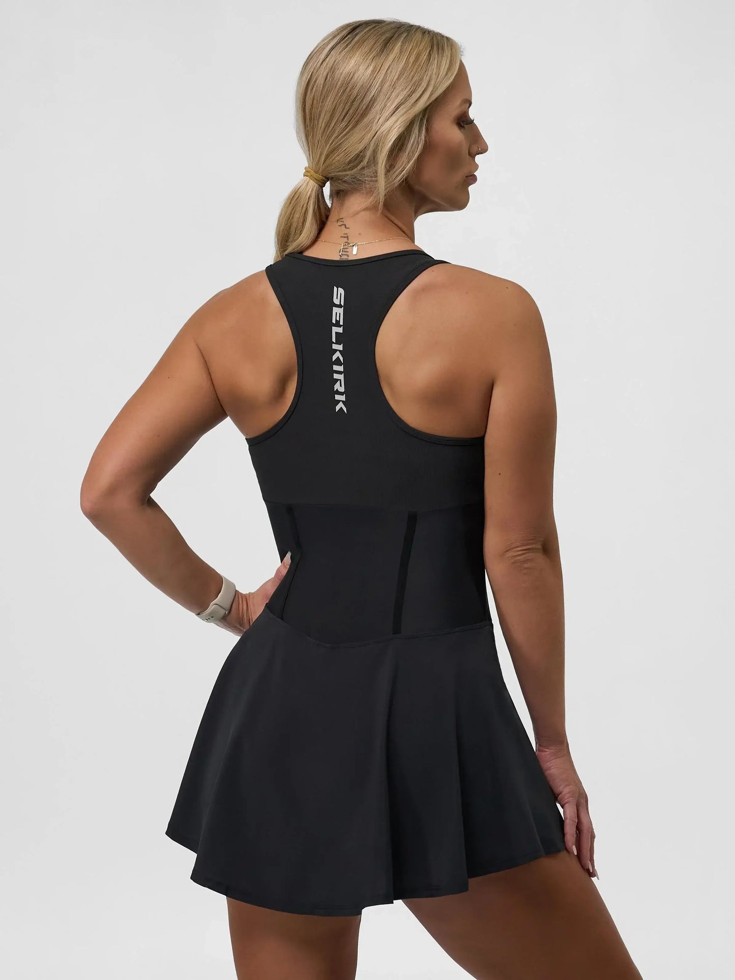 Back view of a woman in the Selkirk Sport Women's Pro Line Pickleball Dress, showcasing its sporty design and flared skirt.
