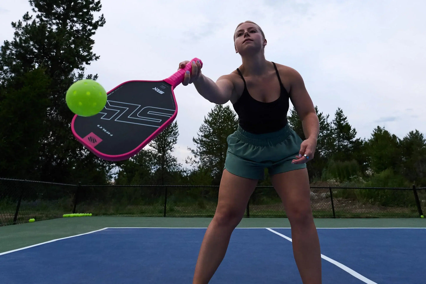 A player holding the SLK HALO Power paddle on the court, ready to hit a pickleball.