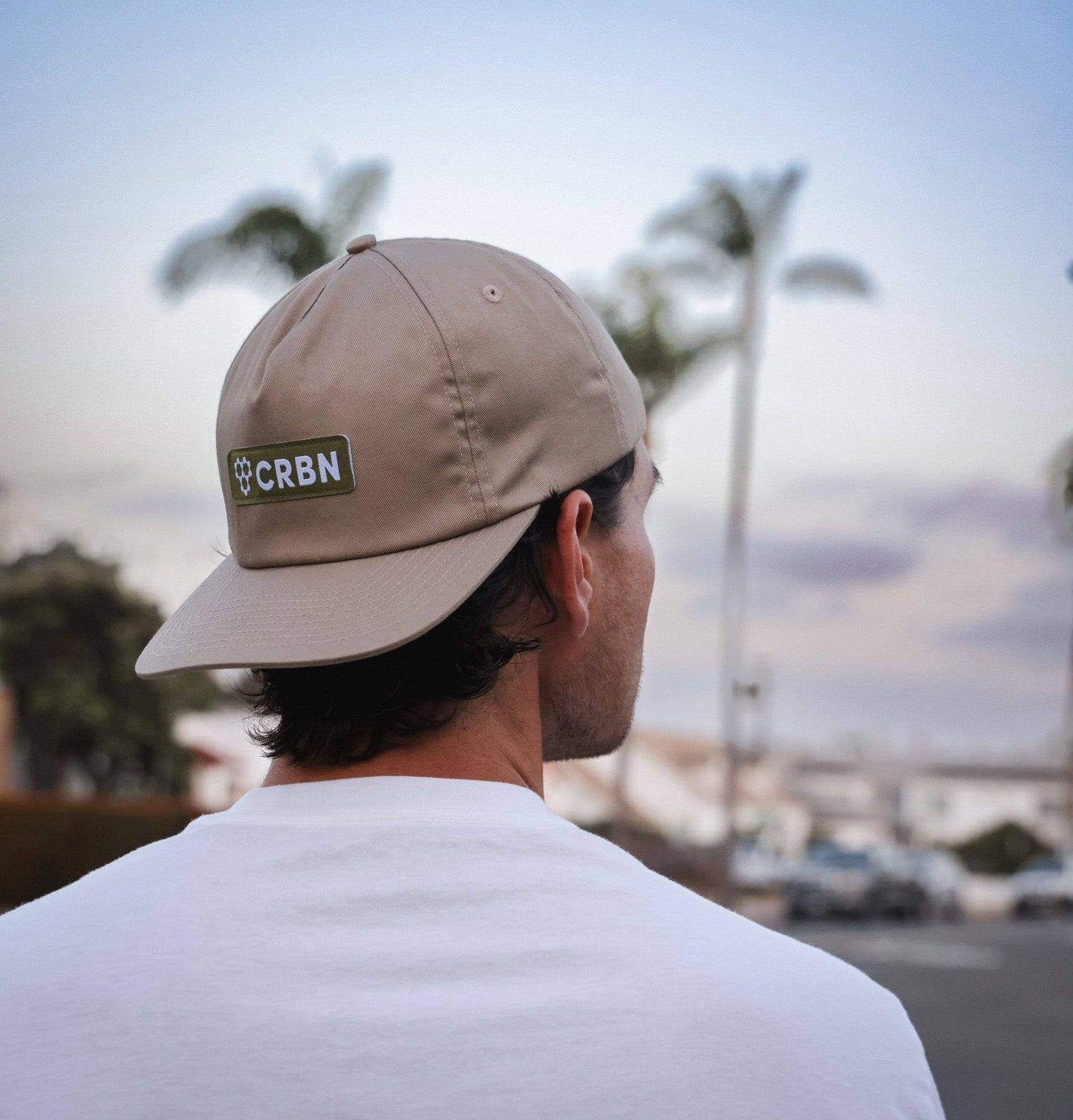 Man wearing a CRBN Essential Snapback Hat with adjustable snapback in a scenic outdoor setting.