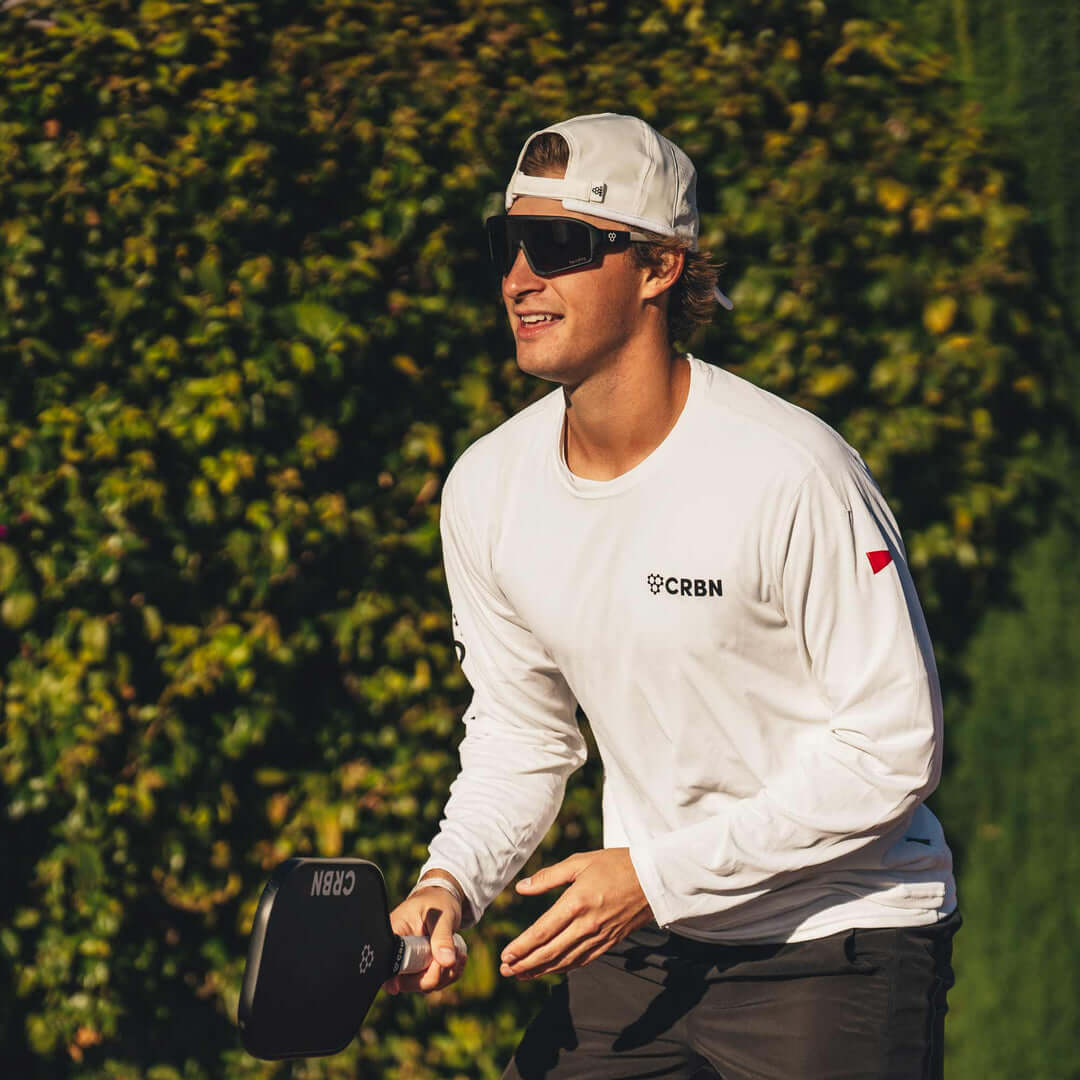 Man wearing CRBN Pivot Pickleball Glasses and playing pickleball outdoors