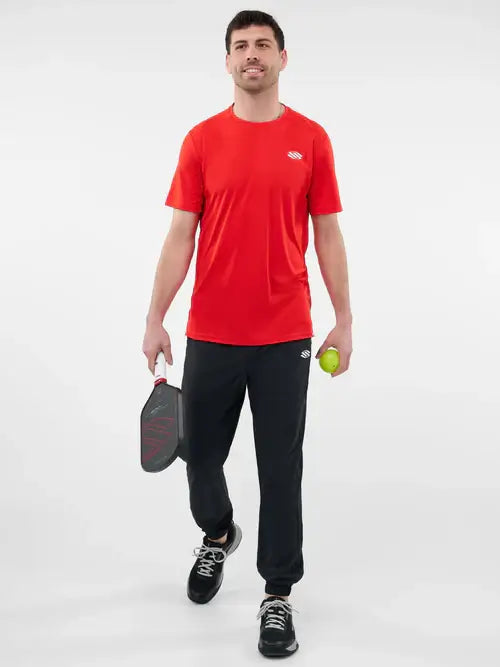 Man in red short sleeve performance tee holding a pickleball paddle and ball, ready for a game.