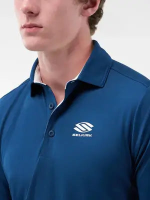 Close-up of model in men’s Essentials Sport-Wik short sleeve polo, featuring a blue color and Belkirk logo.