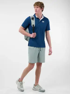Model wearing Men’s Essentials Sport-Wik Short Sleeve Polo with backpack and shorts, showcasing stylish activewear.