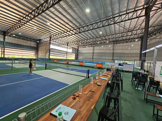 Indoor pickleball courts at DINKiT in Kota Kemuning with players on the court and seating area in the foreground.