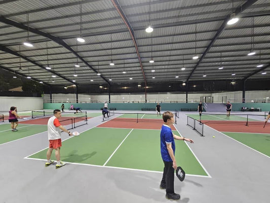 Indoor pickleball courts at Picklepoint in TTDI with players engaged in a game, showcasing vibrant court colors and activity.