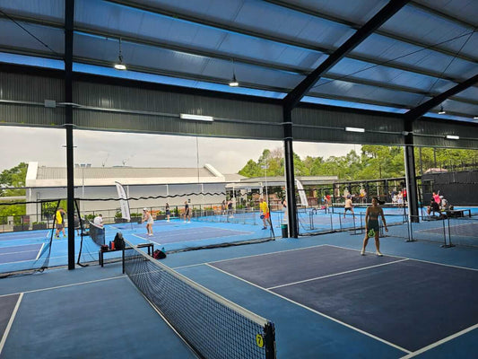 Pickle Social Club pickleball courts at KLGCC with players, surrounded by lush greenery, offering an upmarket and lively sports venue atmosphere.