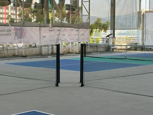 Pickleball courts at Menjelara sports complex with tennis-like flooring and safety nets between courts