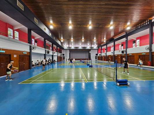 Players enjoying a doubles pickleball match in a large indoor court with bright lighting.