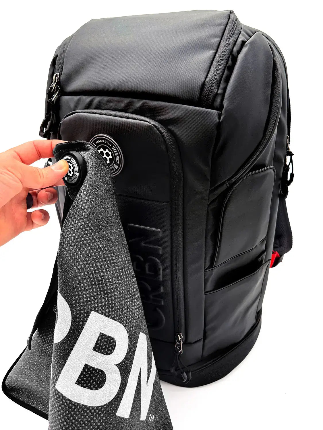 CRBN Pro Team Backpack 2.0 with a hand holding a towel, showcasing its sleek design and durability.