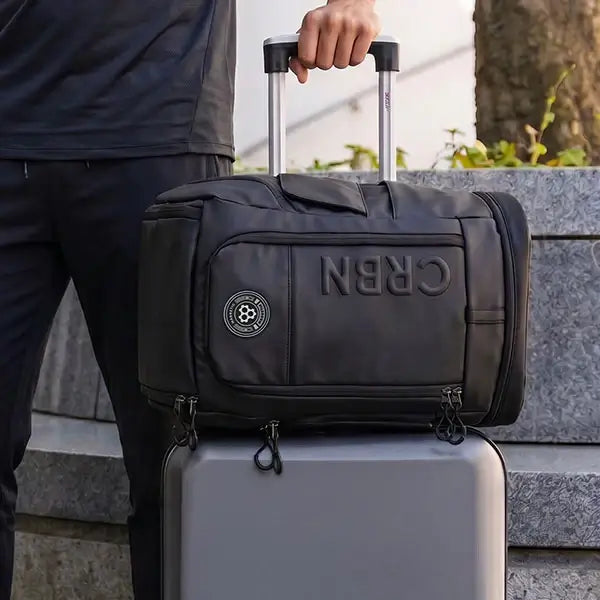 CRBN Pro Team Backpack 2.0 on top of a suitcase, showcasing its sleek design and portability.