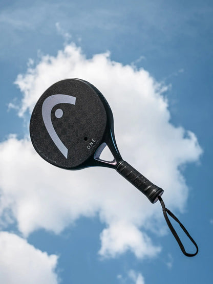 HEAD One Ultralight Padel Racquet against a cloudy sky background.