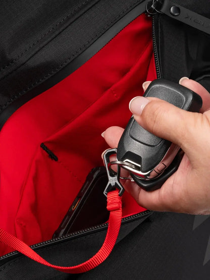 Hand holding a keychain with a clip inside the Selkirk Pro Line 2.0 Pickleball Duffle (45L) red interior pocket.