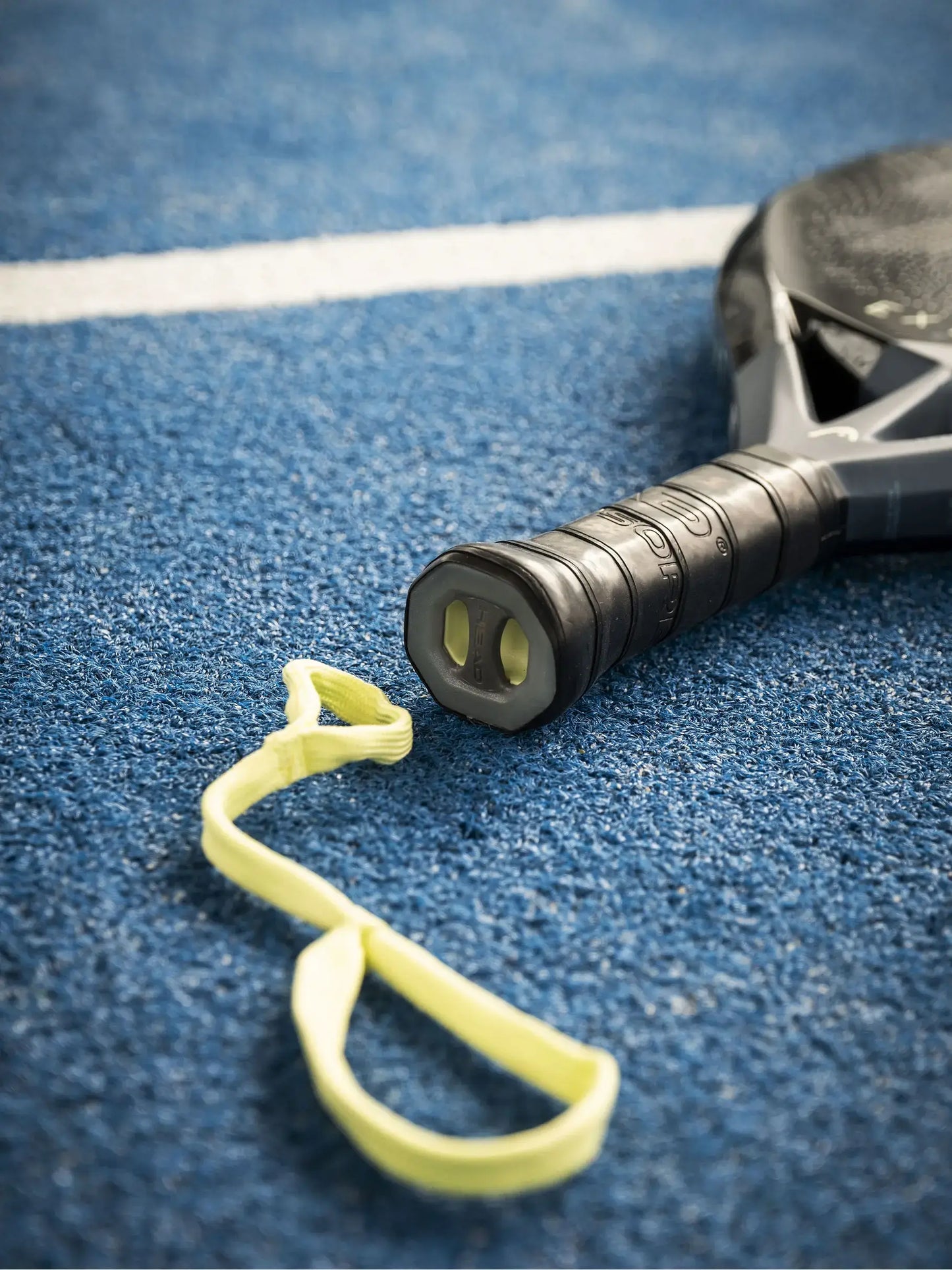 HEAD Extreme One Padel Racquet grip and strap on blue court surface.