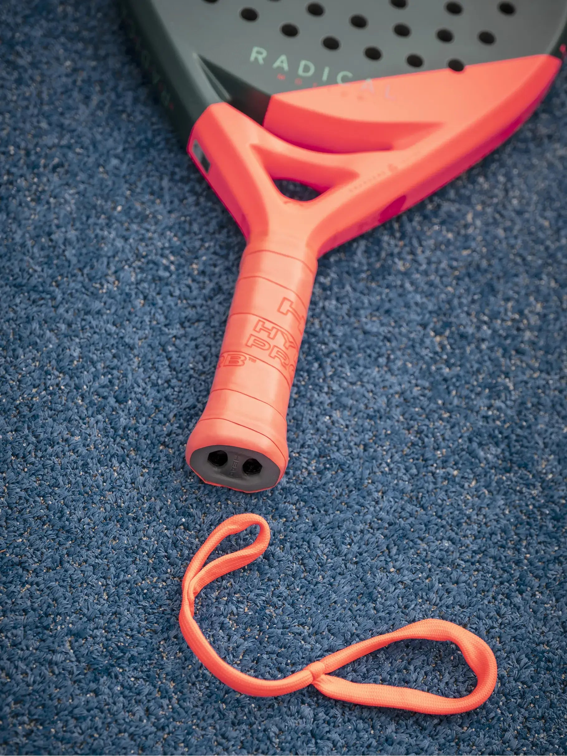 HEAD Radical Motion Padel Racquet grip and wrist strap on blue court surface.