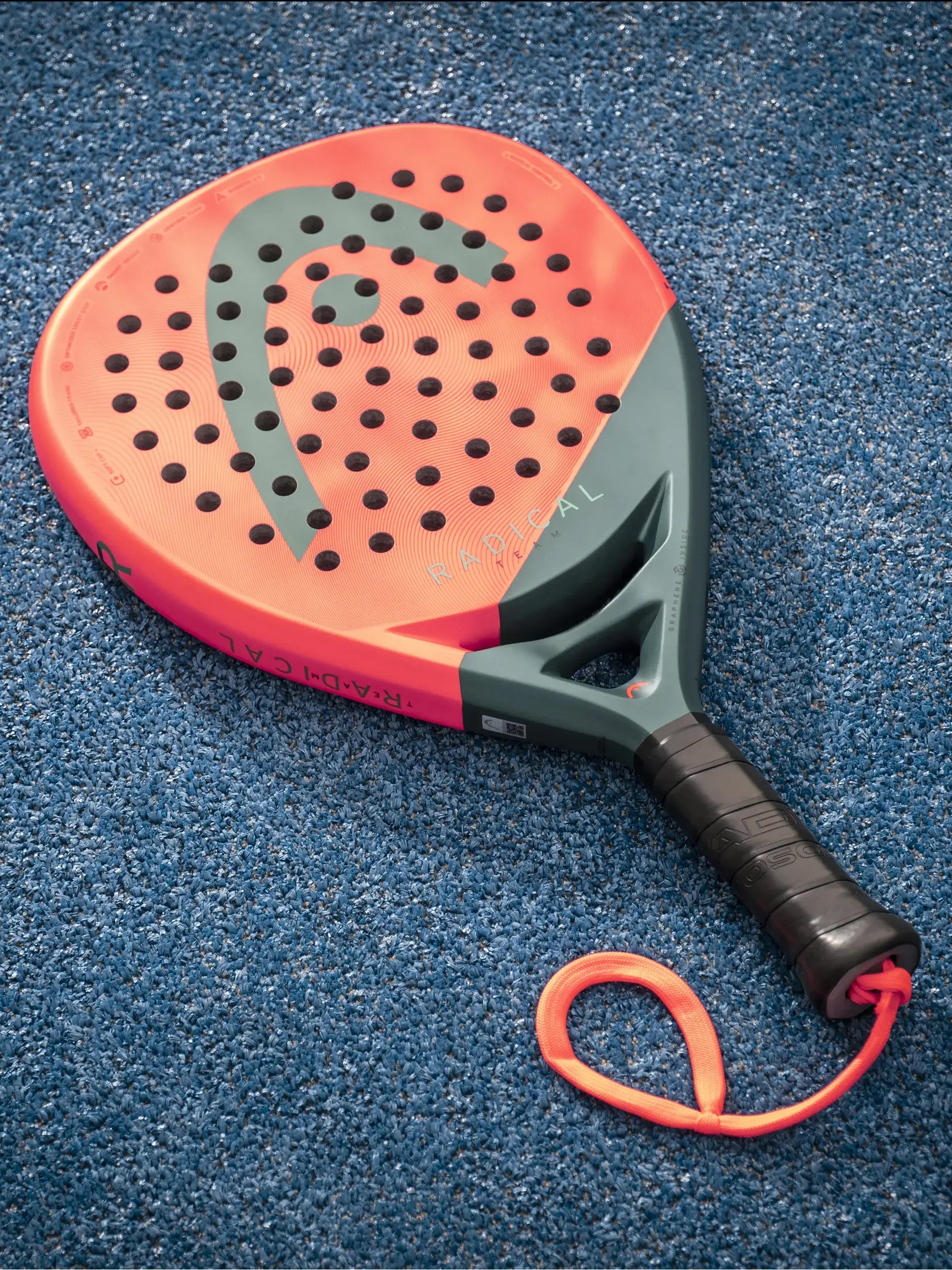 HEAD Radical Team Padel Racquet on blue court surface with vibrant colors and perforated hitting area.