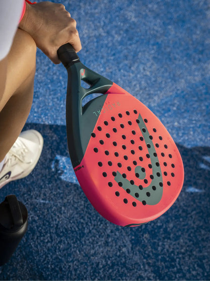 HEAD Radical Team Padel Racquet held by a player on a blue court, showcasing the striking design and perforations.
