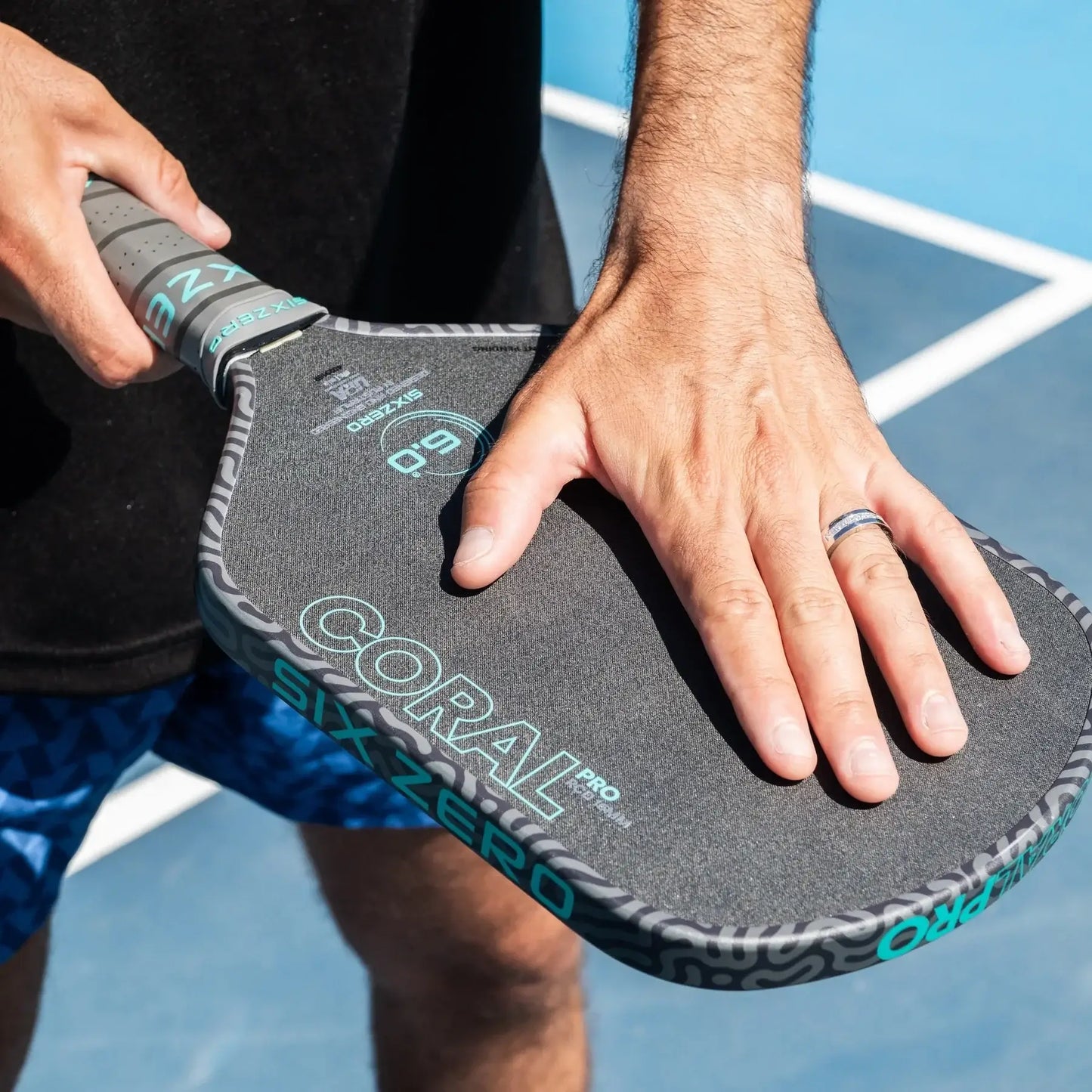 Player holding Six Zero Coral Pro 16mm paddle on court showcasing grip and design details.