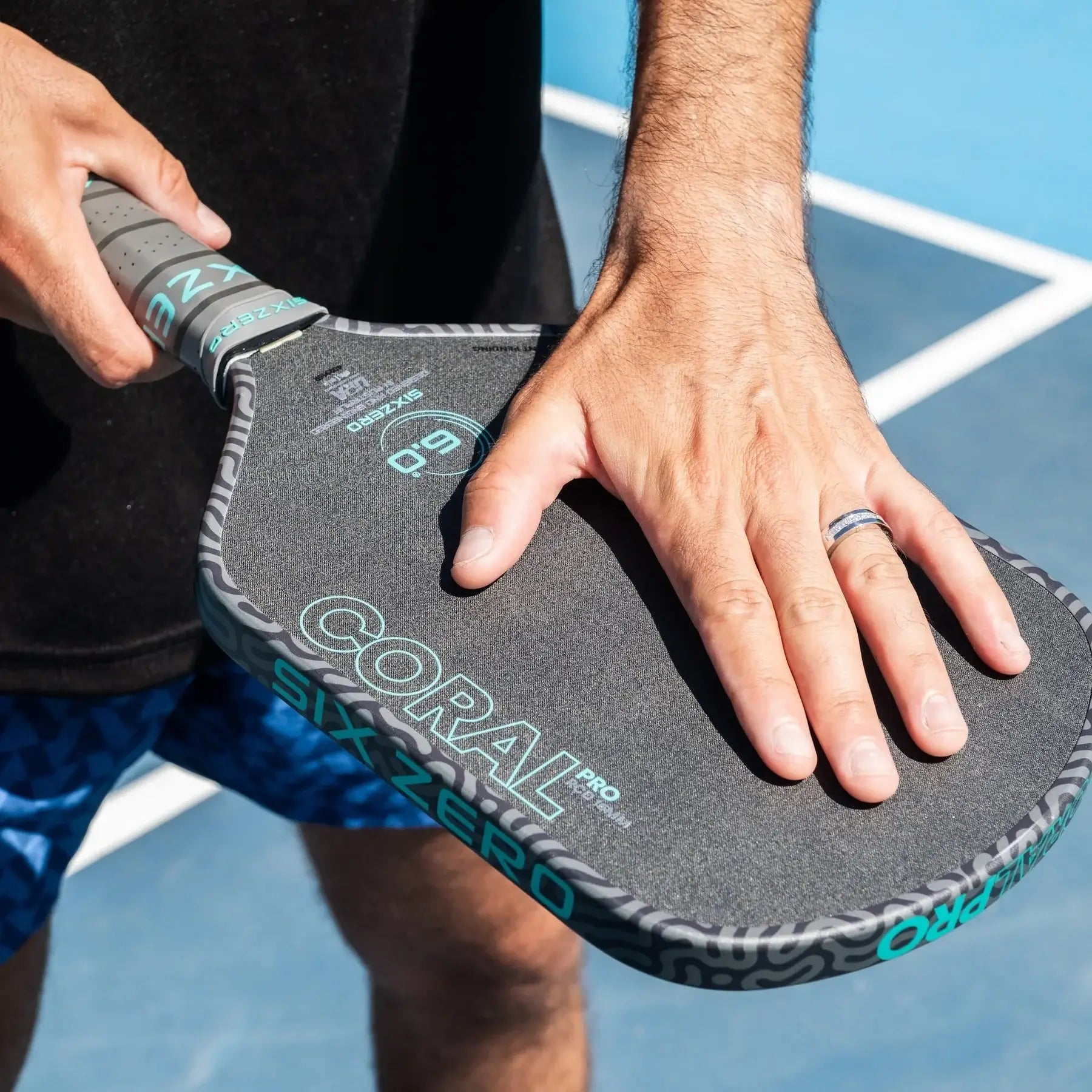 Player holding Six Zero Coral Pro 16mm paddle on court showcasing grip and design details.